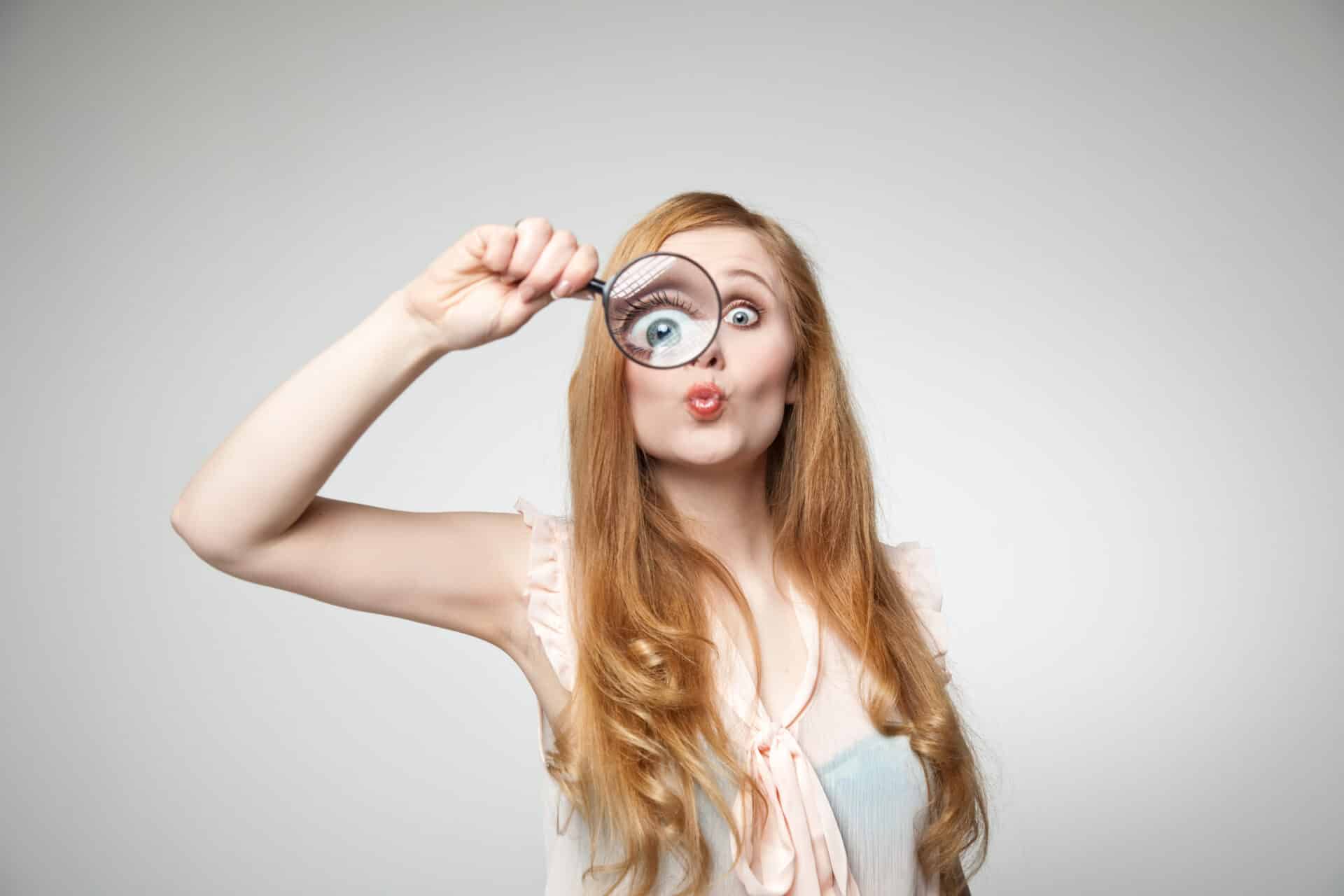 Woman portrait looks through magnifying glass and therefore one eye is very large