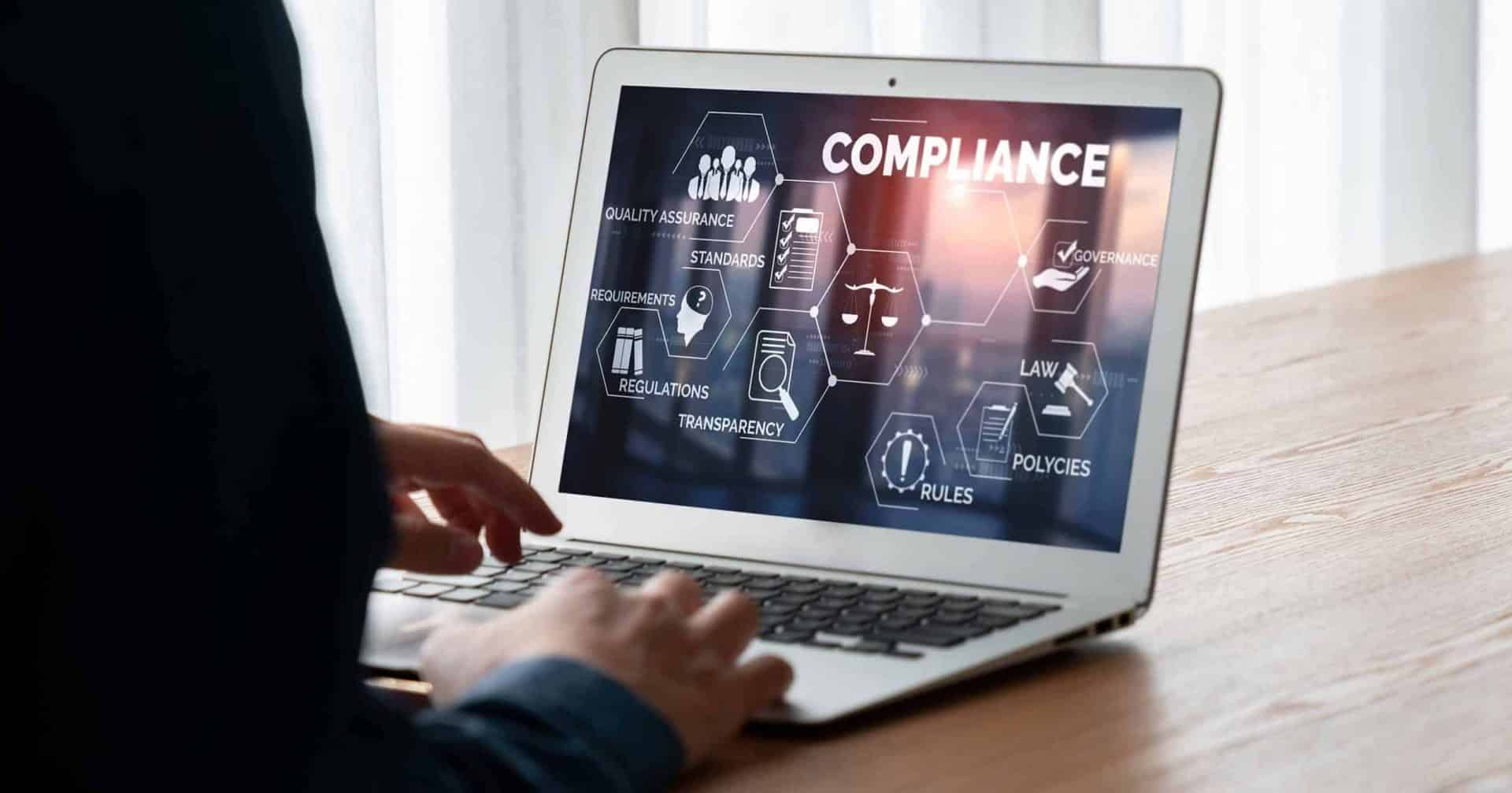 Hier wird ein Laptop gezeigt. Darauf erkennbar sind mehrere Symbole die wichtig zur Produktanforderung der SAP sind. Als große Überschrift steht "Compliance".